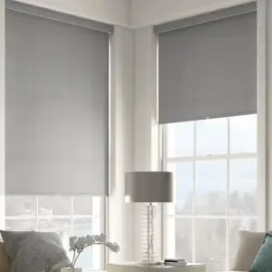 Custom charcoal grey roller solar shades lowering down over large living room windows.